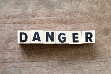 Letter block in word danger on wood background