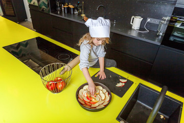 Little girl with chef hat preparing bake homemade holiday apple pie in kitchen. Kid cooking healthy...