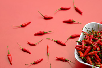Fresh red peppers in a white cup placed on a red background, the view from the top, copy space.