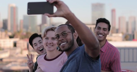 Group of friends taking selfie with city skyline in background - Powered by Adobe