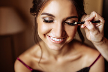 Beautiful bride, makeup artist does the wedding makeup to the girl