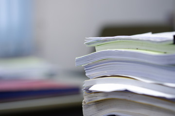 Stack of documents on the desk, background blurred.
