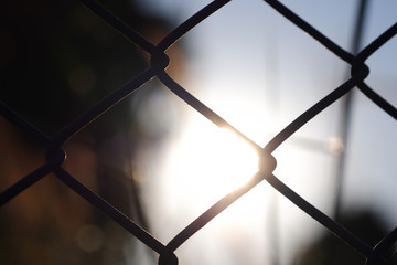Close up of Chain link fence metal grid with amazing sunset background.