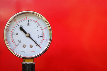 Close up water pressure gauge on red background.