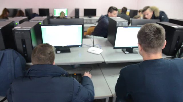 Informatics workshop at university. Young students works on computer during informatics class. Kids studying in classroom.   Education in secondary school. Typing on keyboard in computer class.