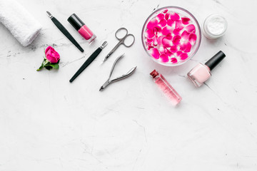 manicure equipment with nail polish and rose petals white stone background top view mockup