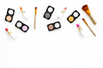 visagiste desk with decorative cosmetics: eyeshadows, lipstick, brush white background top view space for text