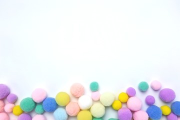 Colorful pom poms on white copy space background 