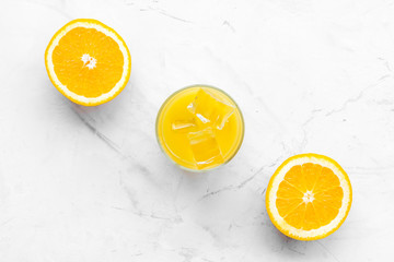 Fresh squeezed orange juice in glass near half cut oranges on white stone background top view pattern copy space