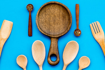 Woodenware set with pan, spoons and forks on blue background top view