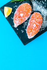 Raw salmon fish on black plates for cooking steaks on blue restaurant kitchen background top view space for text