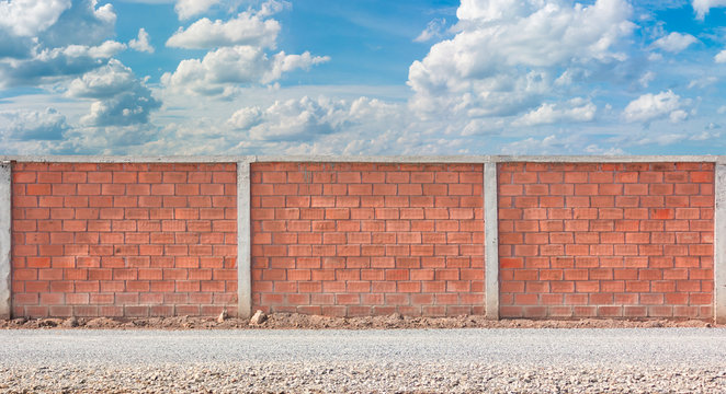 Red brick wall fence with blue sky background, exterior element of rural street industry road area for design
