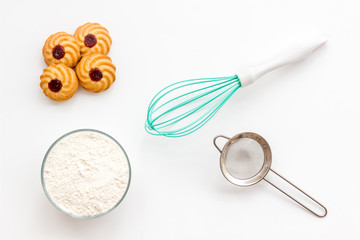 Cook cookies at home concept. Fresh cookies near whisk, flour, sieve on white background top view