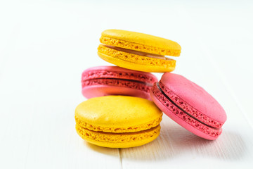 Macaroon cake red and yellow on a white wooden table on a white background.