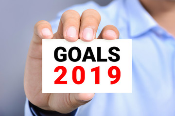 Businessman showing card with text GOALS 2019