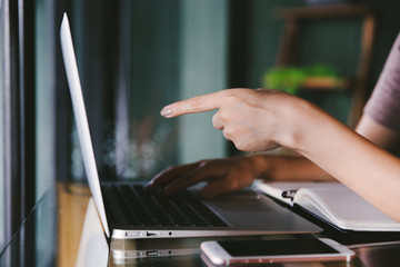 Beautiful young Asian woman working at a coffee shop with computer laptop.