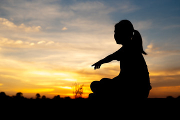 Silhouette of sad and depressed women sitting and pointing at walkway of park with sunset