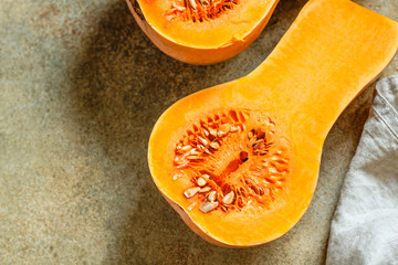 View on raw halves of butternut squash on a kitchen table. Seasonal vegetable food, still life.
