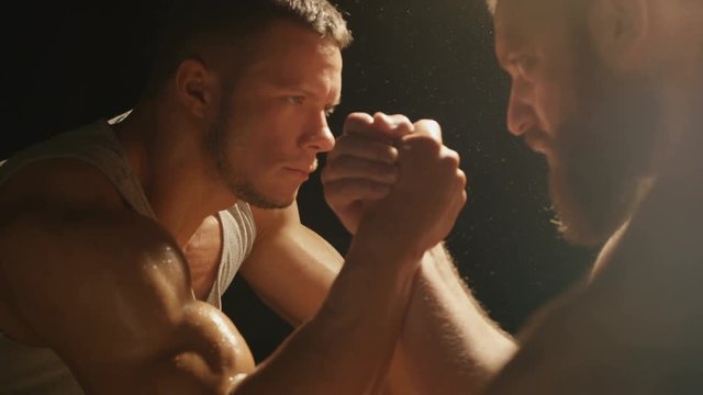 Two strong muscular men engaged in armwrestling