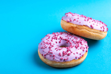 Two delicious lilac donuts with sprinkle on bright blue background