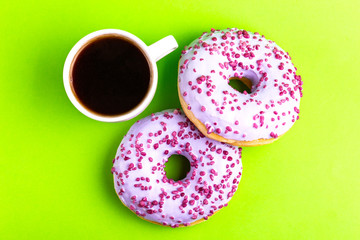 Two delicious lilac donuts with sprinkle and cup of coffee