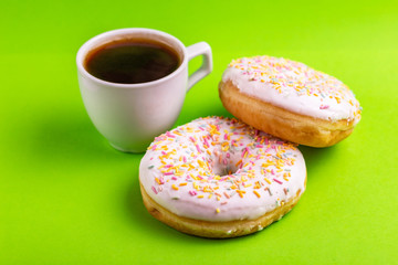 Two delicious vanilla donuts with sprinkle and cup of coffee