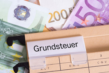 Euro Geldscheine und ein Hängeordner mit den Unterlagen für die Grundsteuer