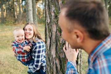 A cute family - mom, dad and son spend fun time outdoors in a beautiful pine forest