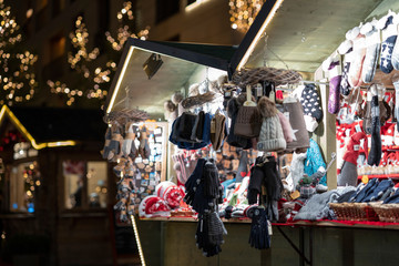 Gloves and hats on christmas market booth in merano south tyrol during night - obrazy, fototapety, plakaty