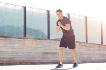 Young and sporty man training outdoor in sportswear. Handsome and fit guy in the street. Sport, health, fitness concept.