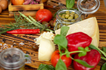 Close up cheese, peppers, green olives, tomatoes and spices. Food background, vegetable composition. Fresh ingredients for preparation salad, pizza, pasta on wooden table. Healthy diet and nutrition.