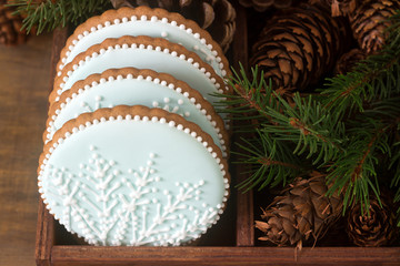 Gingerbreads with a snowflake on a blue background in a wooden box with fir branches and cones. Rustic style.