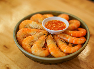 A bowl of shrimp prawns on ice with seafood cocktail sauce.