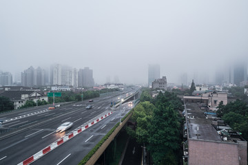 Fototapeta na wymiar Aerial view of buildings and highway in the morning fog