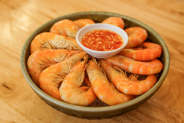A bowl of shrimp prawns on ice with seafood cocktail sauce.