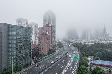 Aerial view of buildings and highway in the morning fog