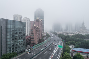 Fototapeta na wymiar Aerial view of buildings and highway in the morning fog