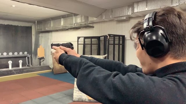 Man aims, holding a gun at a shooting gallery, shooting range.