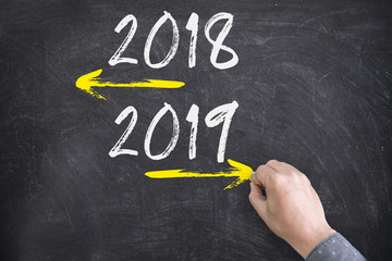 Opposite arrows with Year 2018 versus Year 2019. Hand drawing with chalk on blackboard