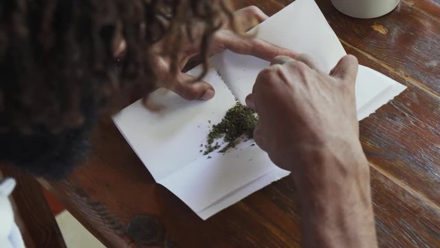 Close up man rolling marijuana joint for smoking