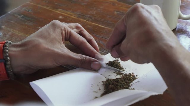 Close up man hands rolling marijuana joint