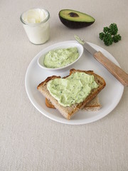 Guacamole mit Avocado, Frischkäse und Petersilie auf einer Scheibe Brot