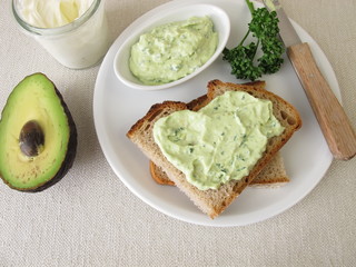 Guacamole mit Avocado, Frischkäse und Petersilie auf einer Scheibe Brot