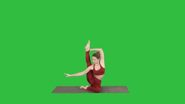 Sporty yogi girl doing fitness practice, stretches, yoga asana Parivritta Kraunchasana on a Green Screen, Chroma Key.