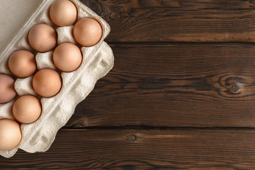 Top view of fresh eggs on paper tray on dark backdrop.