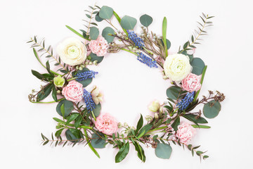 Top view of spring round flower frame wreath with roses, ranunculus, leaves, buds, branches isolated on white background with copyspace. flat lay © uv_group