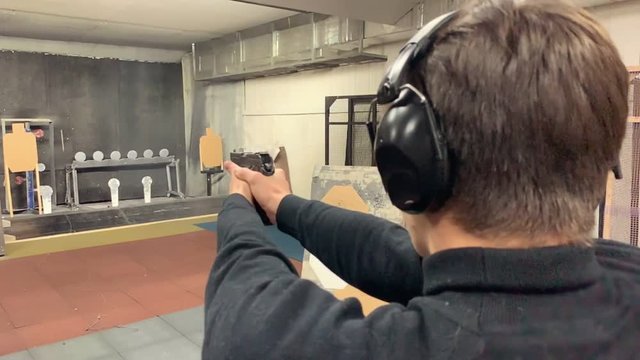 Young man aims, holding a gun at a shooting gallery, shooting range.