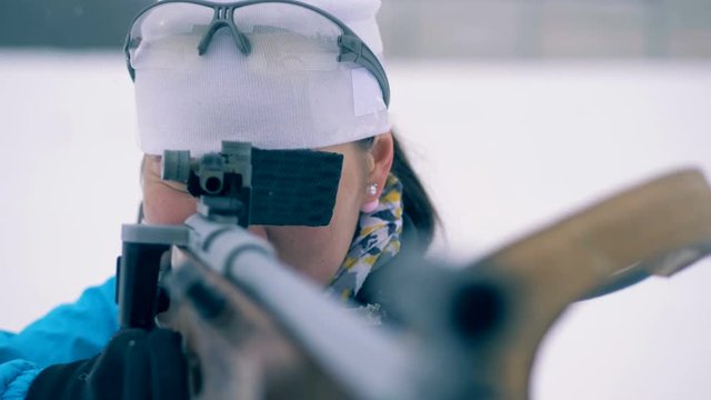 Lady athlete is shooting during biathlon training from firearm