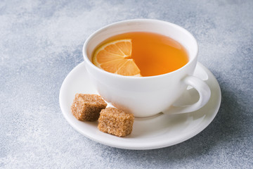 Cup of tea with lemon and brown sugar on the table.