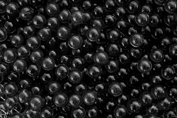 Water black gel balls with bokeh. Polymer gel. Silica gel. Balls of black hydrogel. Crystal liquid ball with reflection. Black texture background. Macro
